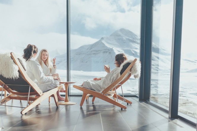 3 people enjoying drinks in spa chairs with views of a mountain.